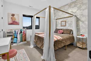Bedroom with wallpapered walls and light colored carpet
