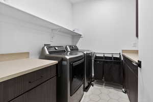 Laundry area with cabinet space, separate washer and dryer, and light tile patterned floors