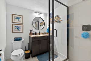Full bath featuring a stall shower, vanity, a textured ceiling, and light tile patterned flooring