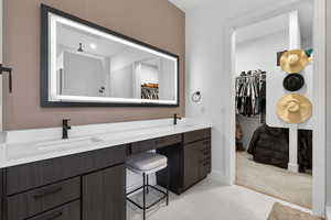 Bathroom featuring a spacious closet, double vanity, light carpet, and light tile patterned floors