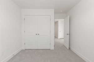 Unfurnished bedroom with light carpet and a closet