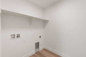 Washroom with hookup for a washing machine, light wood-style flooring, and hookup for an electric dryer
