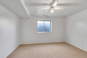 Empty room with light carpet and a ceiling fan