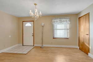 Foyer featuring healthy amount of natural light, light wood-style flooring, and a chandelier