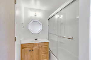 Full bath featuring vanity and bath / shower combo with glass door