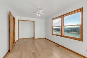 Unfurnished bedroom featuring light wood finished floors, a ceiling fan, and a closet