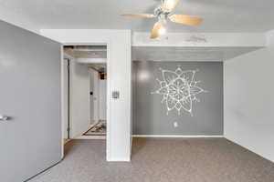 Unfurnished room featuring light carpet, a textured ceiling, and a ceiling fan
