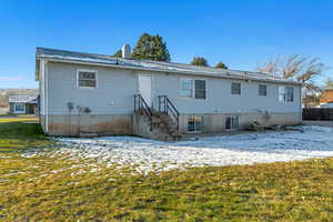 Snow covered rear of property with a chimney and a yard