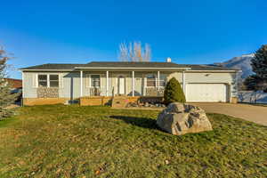 Single story home with a porch, concrete driveway, an attached garage, a chimney, and roof with shingles