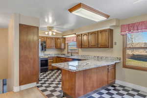 Kitchen featuring light flooring, brown cabinets, a peninsula, and electric range oven