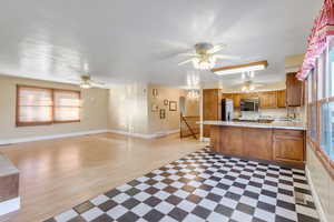 Kitchen with open floor plan, ceiling fan, a peninsula, brown cabinets, and black microwave
