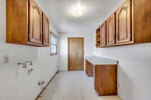 Laundry area with cabinet space, gas dryer hookup, a textured ceiling, and light floors