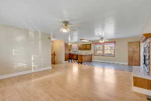 Living room with a ceiling fan, a tiled fireplace, and light wood-style flooring