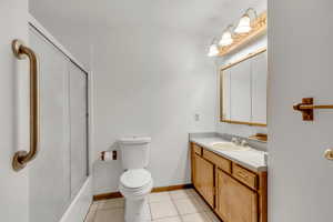 Full bath featuring vanity, light tile patterned floors, and combined bath / shower with glass door