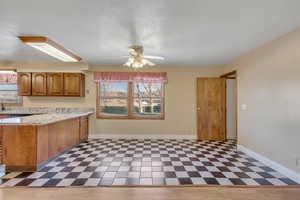 Kitchen with brown cabinets, light flooring, ceiling fan, and a peninsula