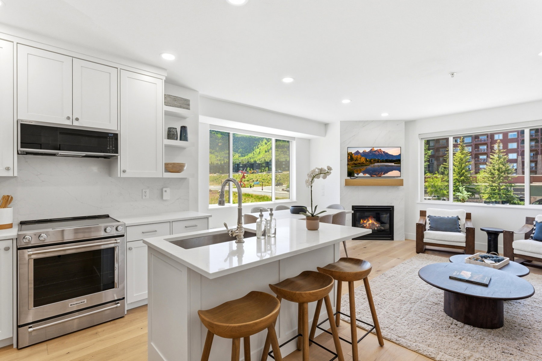 Open-concept living space featuring a modern kitchen with a large island, stainless steel appliances, and white cabinetry