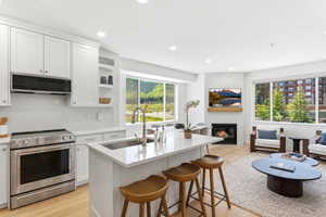 Open-concept living space featuring a modern kitchen with a large island, stainless steel appliances, and white cabinetry