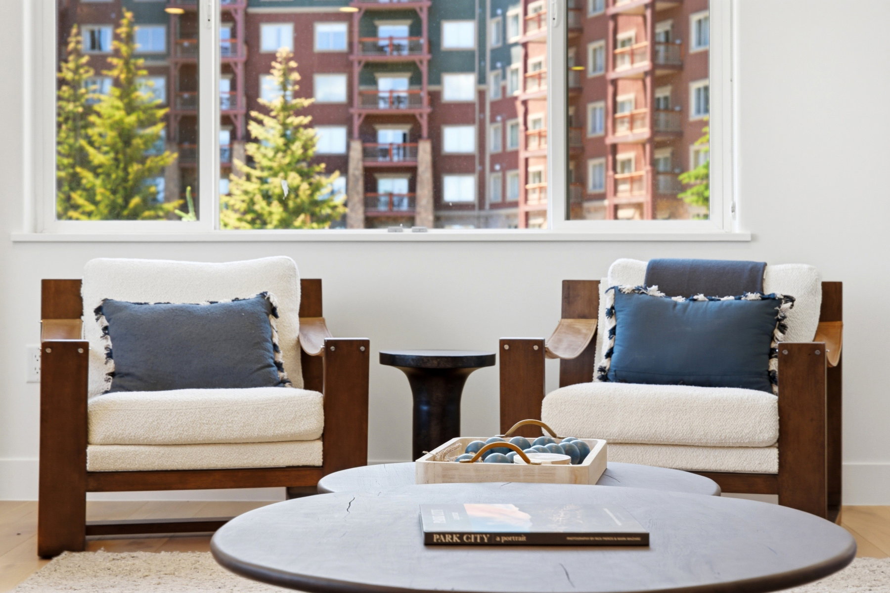 Bright interiors featuring a large window with white trim, wood-finish flooring, and crisp white walls
