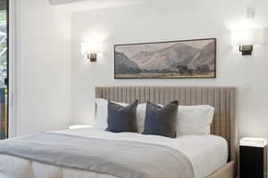 Bedroom featuring a channeled upholstered headboard, white walls, and dual wall-mounted sconces