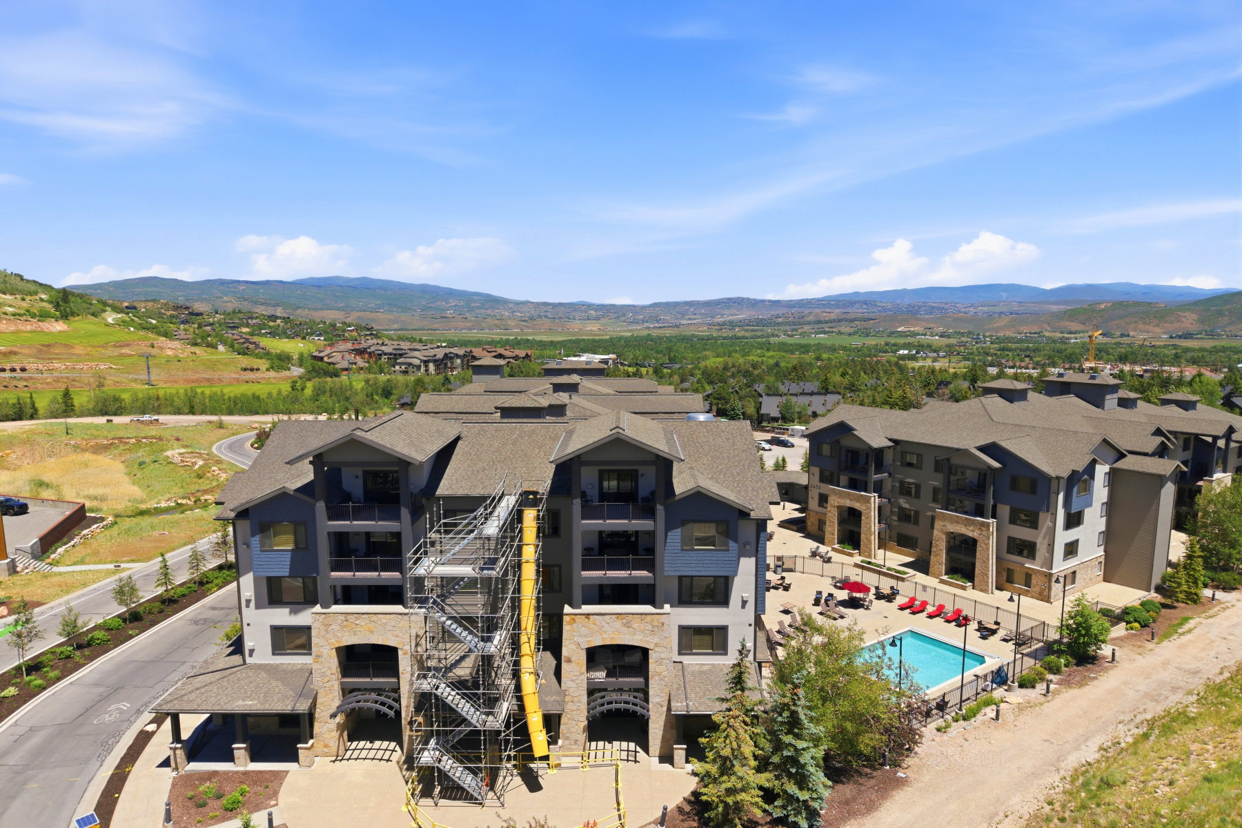 Contemporary multi-story buildings featuring stone and siding exteriors, balconies, and a communal outdoor pool area