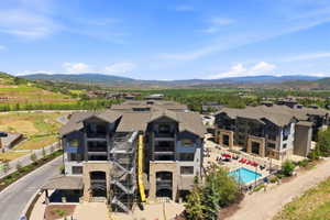 Contemporary multi-story buildings featuring stone and siding exteriors, balconies, and a communal outdoor pool area