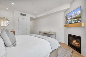 Bedroom featuring wood finished floors, recessed lighting, and a fireplace