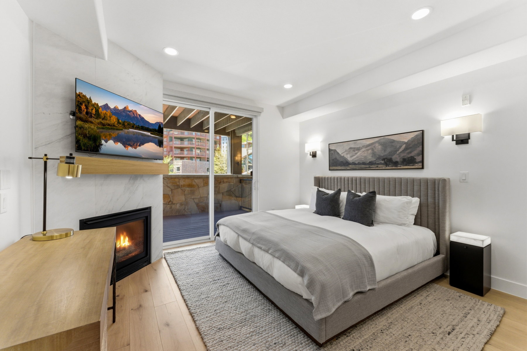 Bedroom featuring a stone-clad fireplace with a natural wood mantel, light wood-finish flooring, recessed lighting, and direct access to an outdoor patio through sliding glass doors