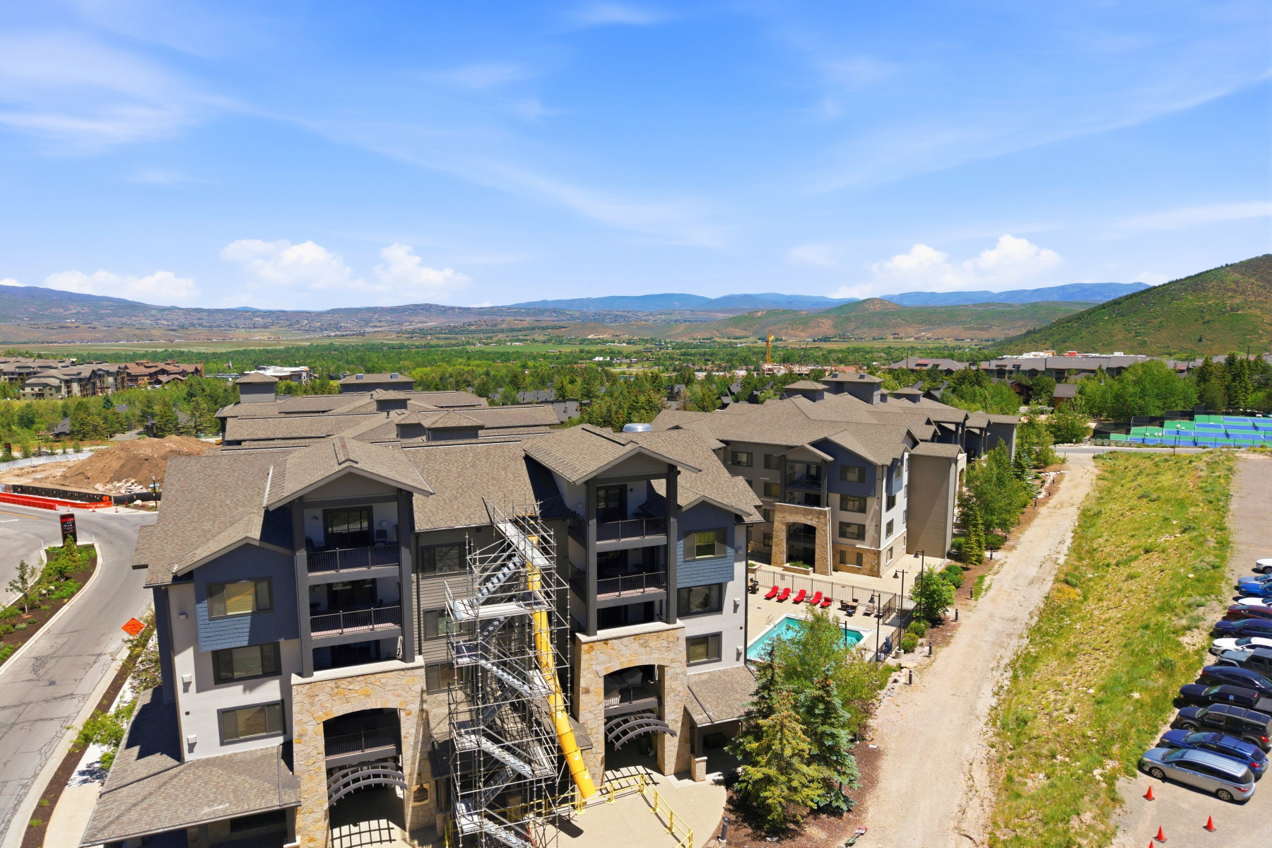 Multi-story residential buildings featuring stone and siding exteriors, balconies, and a central swimming pool with lounge seating