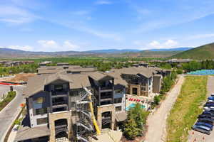 Multi-story residential buildings featuring stone and siding exteriors, balconies, and a central swimming pool with lounge seating