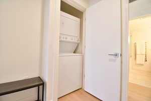Laundry room with light wood finished floors and stacked washer and clothes dryer
