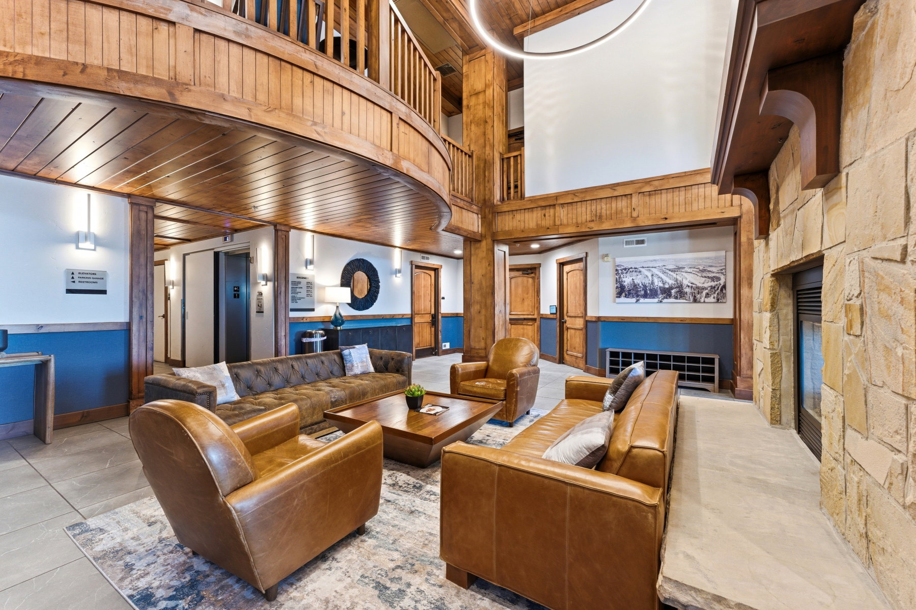 Spacious common area featuring a stone accent wall with fireplace, wood-paneled ceilings, and tile flooring