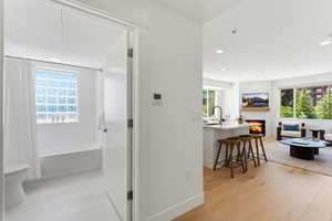 Open-concept living space with light wood-finish flooring, recessed lighting, and a white fireplace feature
