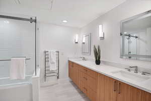 Bathroom with double vanity, a shower with shower door, a tub to relax in, and recessed lighting