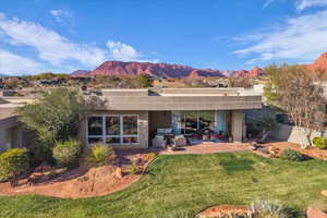 Rear view of house with a mountain view, stucco siding, a patio area, a yard, and an outdoor living space