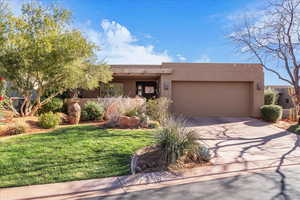Southwest-style home featuring stucco siding, concrete driveway, an attached garage, and a front yard