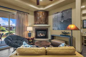 Living room featuring a ceiling fan and a glass covered fireplace