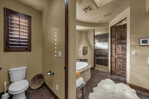 Bathroom with a bath, tiled shower, and dark tile patterned flooring