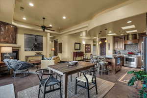 Dining room with a glass covered fireplace, recessed lighting, a ceiling fan, and a tray ceiling