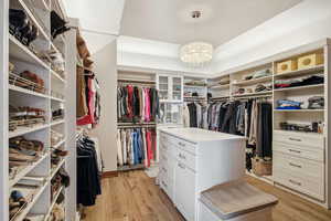 Walk in closet featuring light wood-type flooring and a chandelier