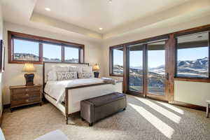 Carpeted bedroom with a mountain view, access to exterior, a tray ceiling, and recessed lighting