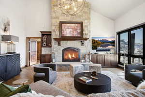 Living room featuring a fireplace, wood finished floors, high vaulted ceiling, and a chandelier