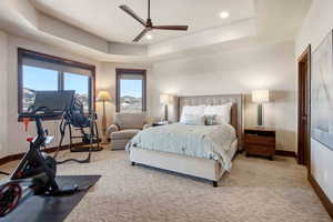 Carpeted bedroom with a raised ceiling, ceiling fan, and recessed lighting