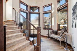 Entrance foyer with light wood-type flooring, stairway, and a towering ceiling