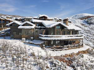 Snow covered house with stone siding, a chimney, and a mountain view
