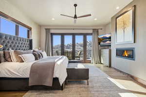 Bedroom featuring wood finished floors, a glass covered fireplace, ceiling fan, and recessed lighting
