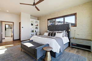 Bedroom with wood finished floors, a ceiling fan, and wallpapered walls