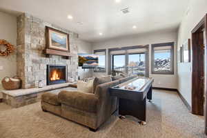 Living area featuring a fireplace, light colored carpet, a textured ceiling, and recessed lighting