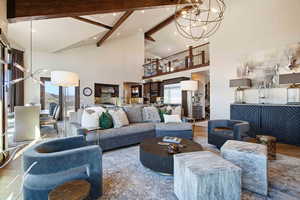 Living area with a chandelier, high vaulted ceiling, beamed ceiling, and wood finished floors