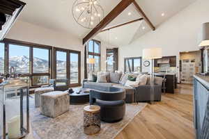 Living area with high vaulted ceiling, light wood-style floors, a mountain view, beamed ceiling, and a chandelier