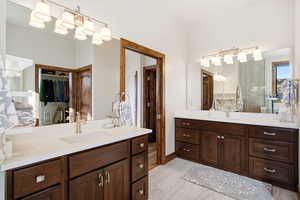 Bathroom featuring two vanities and a walk in closet